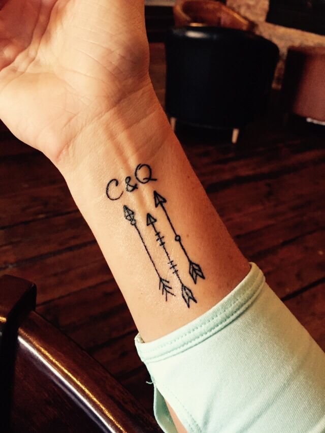 A Small Tattoo On The Wrist Of A Woman With An Arrow And Two Arrows In It